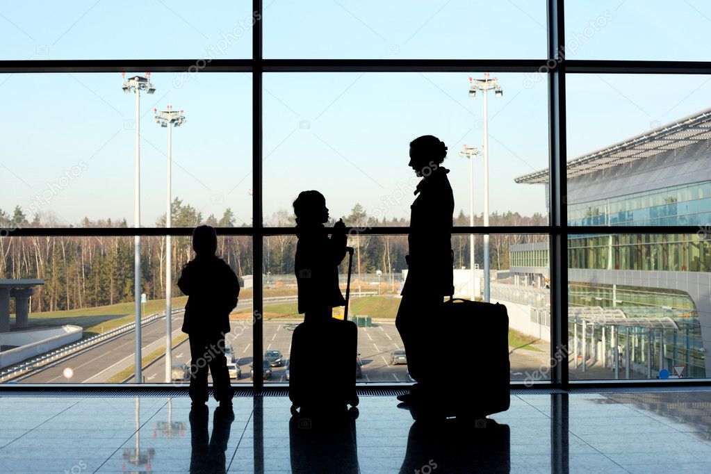 Silhouette of mother, son and daughter with luggage standing nea