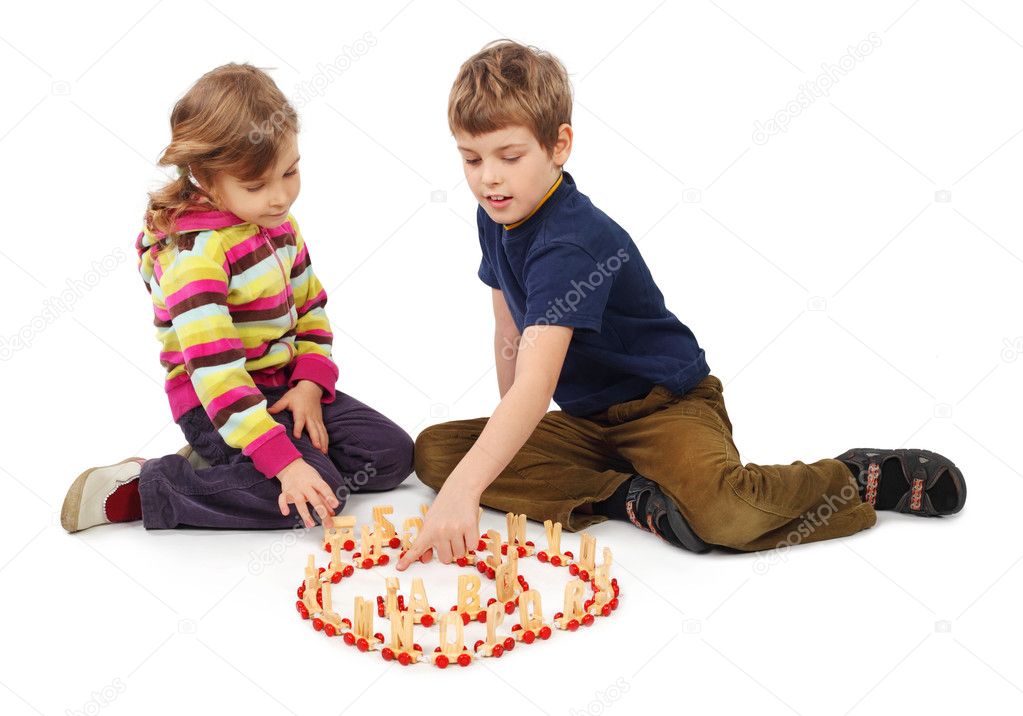 Little boy and girl playing with wooden railway sitting on floor