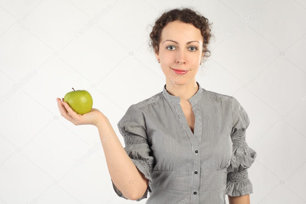 Young attractive woman holding an apple in one hand, looking at