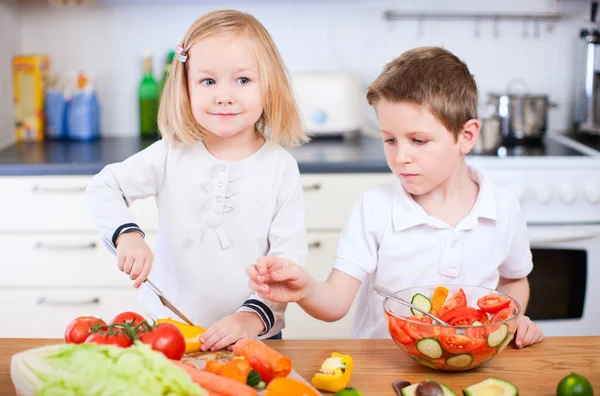 Двое маленьких детей делают салат — стоковое фото