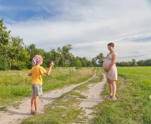 Kleine jongen maken zeepbellen met zijn regnant moeder — Stockfoto