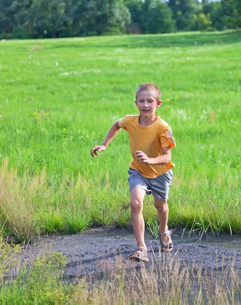 Маленький мальчик бежит по зеленому лугу — стоковое фото