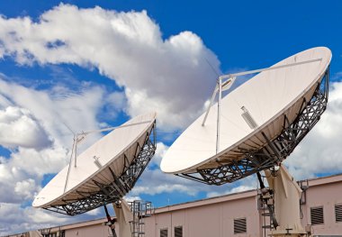 Satellite TV antenna on blue sky and clouds background clipart