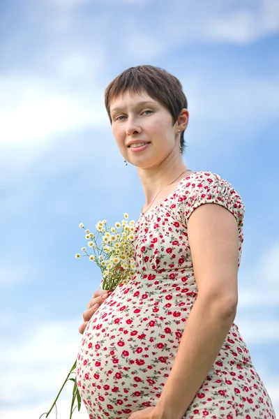Mulher grávida com buquê de camomila — Fotografia de Stock
