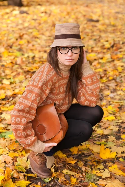 Ung flicka med handväska på gula blad bakgrund — Stockfoto