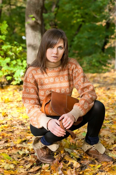 Giovane ragazza con borsetta seduta nella foresta — Foto Stock