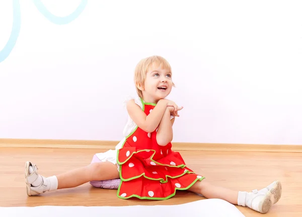 Cheerful little girl in red apron — Stock Photo, Image