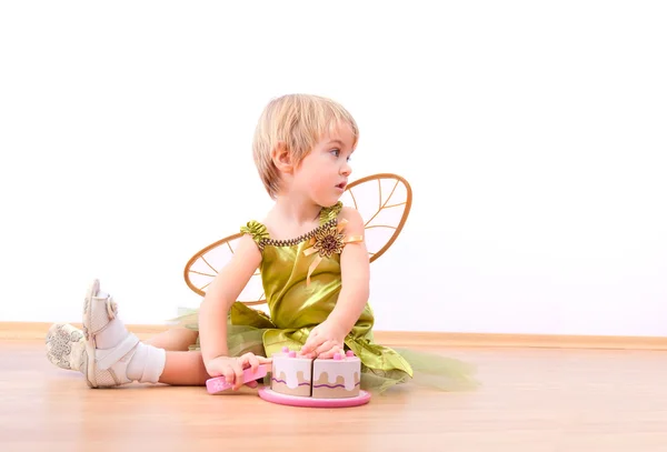 Весела фея маленька дівчинка ріже іграшковий торт — стокове фото