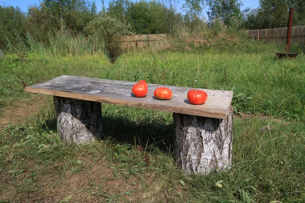 Tomates vermelhos no banco de madeira — Fotografia de Stock
