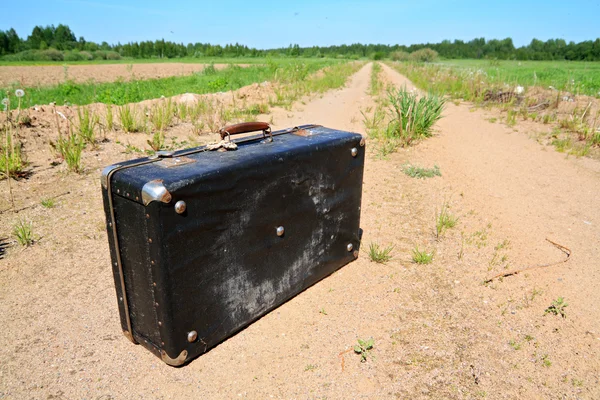 田舎道で古い小型スーツケース — ストック写真