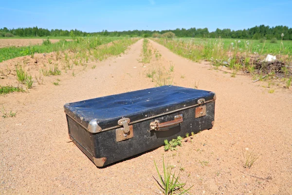 田舎道で古い小型スーツケース — ストック写真