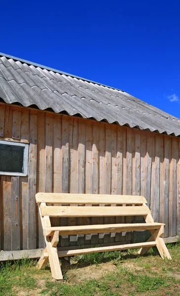 Деревянная скамейка возле деревянной стены — стоковое фото
