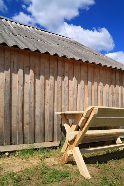 Banco de madeira perto de parede de madeira — Fotografia de Stock