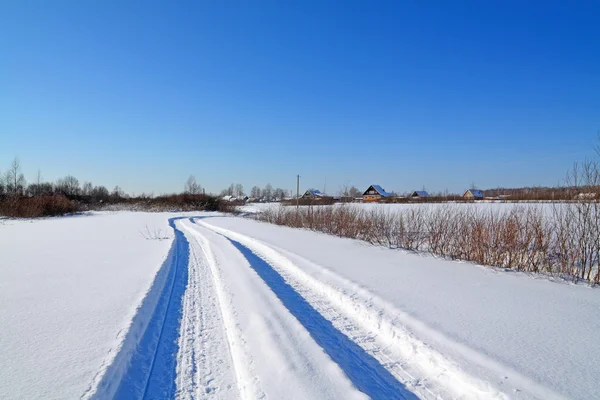 Снежная дорога около зимы в деревнях — стоковое фото