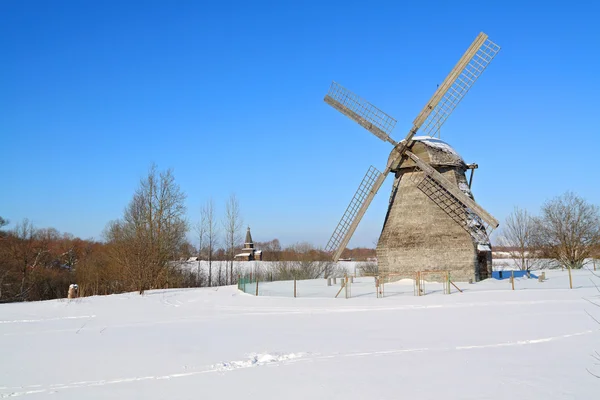 Veroudering molen op sneeuwveld — Stockfoto