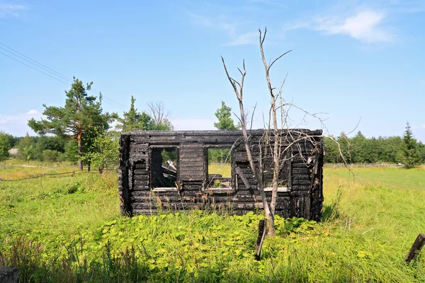 Burned house on green field — Stock Photo, Image
