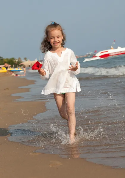 Kleines Mädchen rennt den Strand hinunter. — Stockfoto