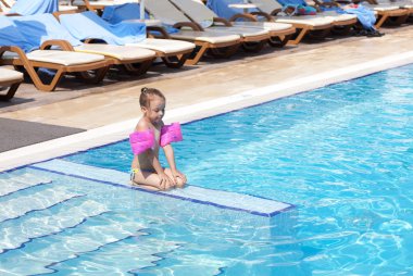 Little girl on the side of the pool. clipart