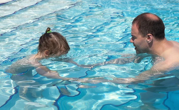 Папа учит свою дочь плавать в бассейне . — стоковое фото