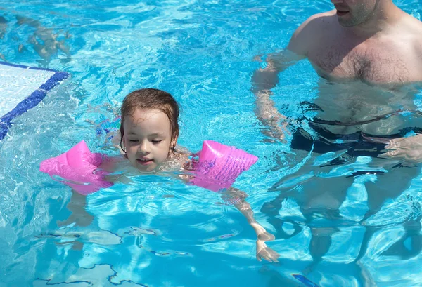 Menina aprende a nadar na piscina — Fotografia de Stock