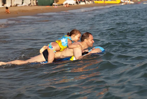 Uomo con figlia che cavalca su una zattera gonfiabile in mare . — Foto Stock