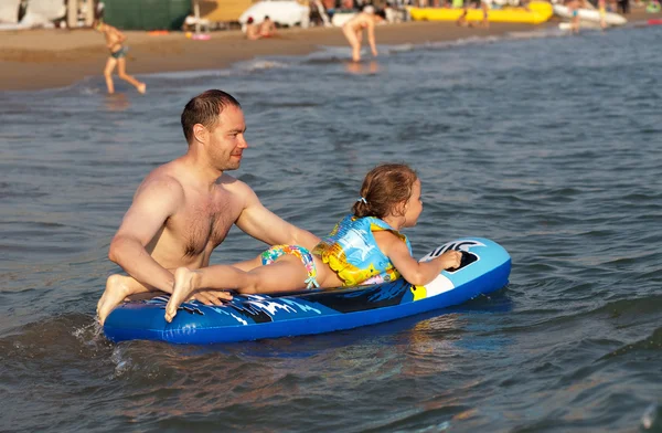 Папа держит ребенка верхом на волне моря — стоковое фото