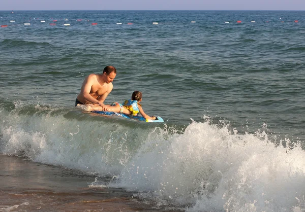 Dad holds child riding a wave of the sea — Stock Photo, Image