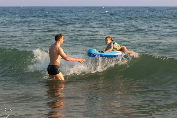 Papa attrape un enfant chevauchant une vague de la mer . — Photo