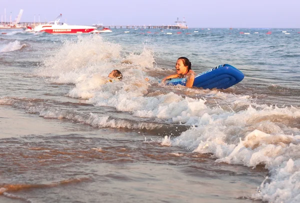 Радостная девочка и ребенок катаются по морским волнам . — стоковое фото