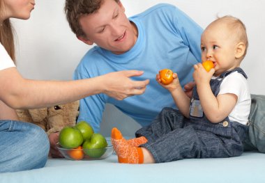 çocuğun aile içinde mandalina yiyor.