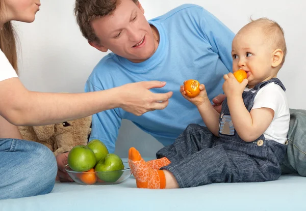 Малюк в сім'ї їсть мандарини . — стокове фото