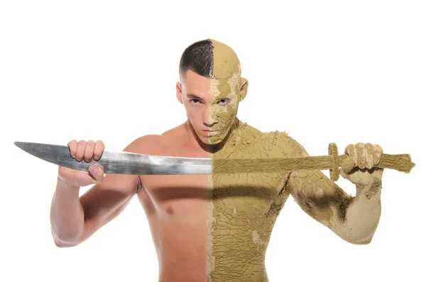 Молодий чоловік наполовину розмазаний глиною з мечем — стокове фото