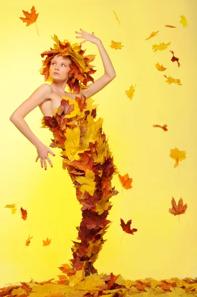 Kvinna i klänning av blad och avlövning — Stockfoto