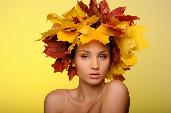 Beautiful woman with autumn leaves on yellow — Stock Photo, Image