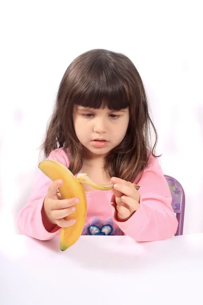 Klein meisje schillen van een banaan — Stockfoto