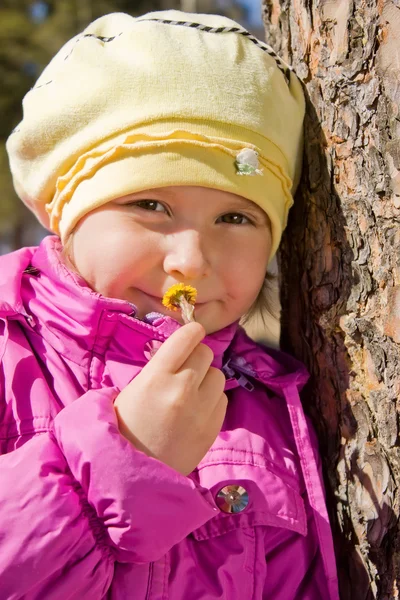Menina cheirando uma flor amarela . — Fotografia de Stock