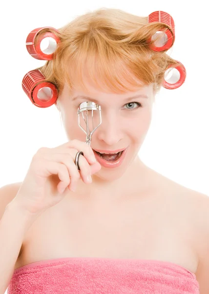 Woman in curlers curl eyelashes on a white background. — Stock Photo, Image