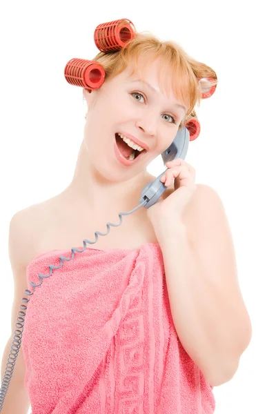 En kvinna i papiljotter prata i telefon på en vit bakgrund. — Stockfoto