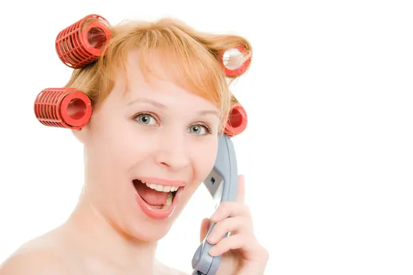 Una mujer en rulos hablando por teléfono sobre un fondo blanco . — Foto de Stock
