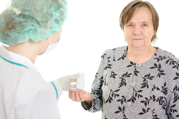 Der Arzt nimmt der alten Frau eine Flasche Tabletten. — Stockfoto