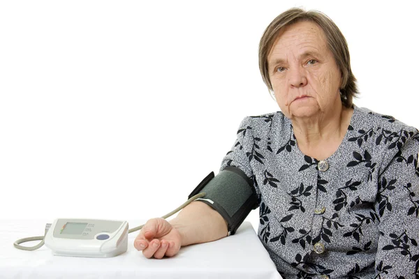 An elderly woman with a sphygmomanometer on a white background. — Stock Photo, Image