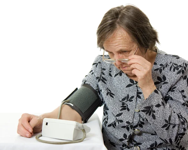 Egy idős nő, egy vérnyomásmérő, fehér alapon. — Stock Fotó