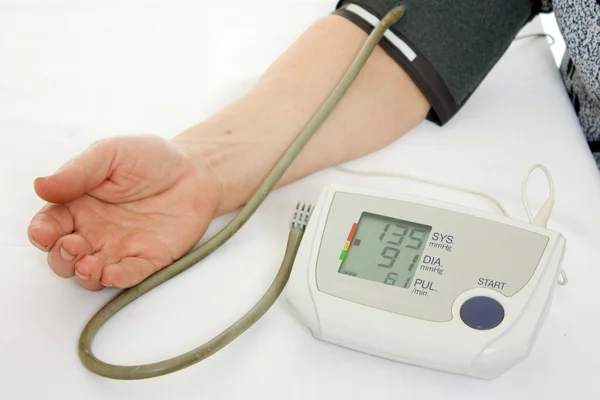 Hand an elderly woman with a sphygmomanometer on a white background. — Stock Photo, Image