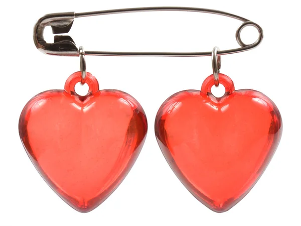 Deux cœurs rouges sont joints avec une épingle sur un fond blanc . — Photo