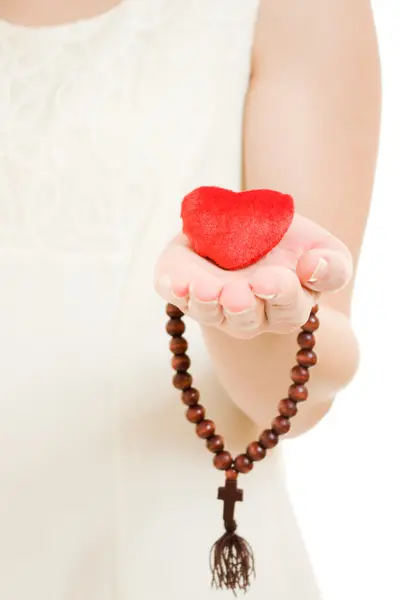Mulher segura o coração e o rosário em sua mão sobre um fundo branco . — Fotografia de Stock