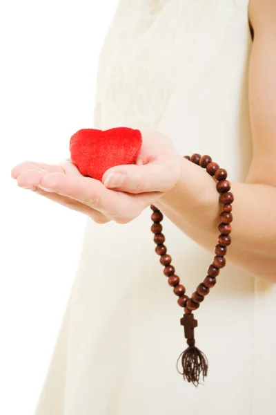 Vrouw houdt het hart en de rozenkrans in zijn hand op een witte achtergrond. — Stockfoto