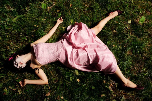 Девочка лежит на траве, как труп — стоковое фото