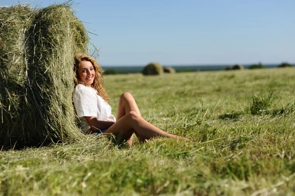 Woman sit near haystack — Stock Photo, Image