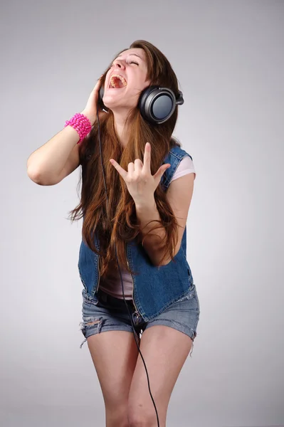 Lustige junge Frau in Jeansbekleidung hört Musik — Stockfoto