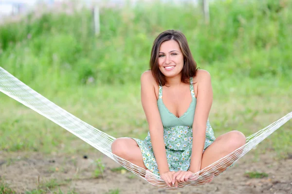 Mujer sonriente sentarse en la hamaca — Foto de Stock